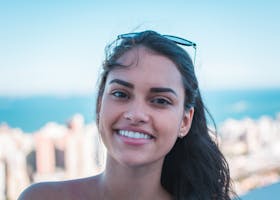 Portrait of a happy woman smiling with sunglasses on head, city skyline view.